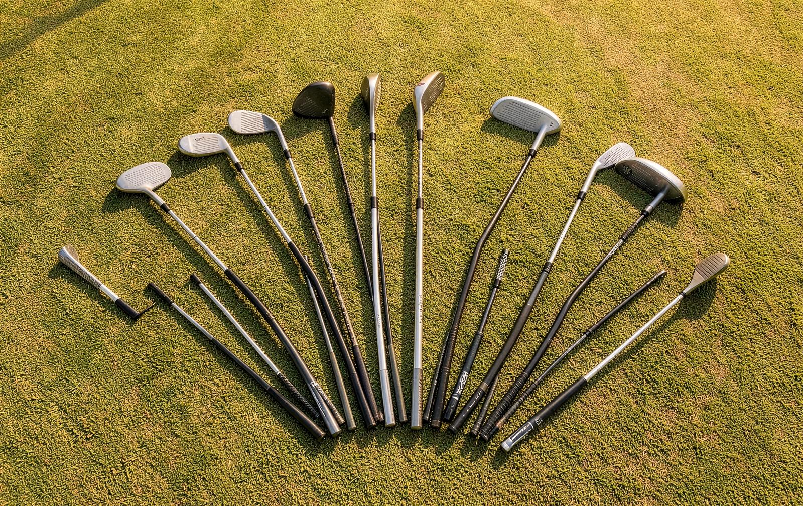 Overhead view of a full set of fourteen golf clubs fanned out on fairway grass